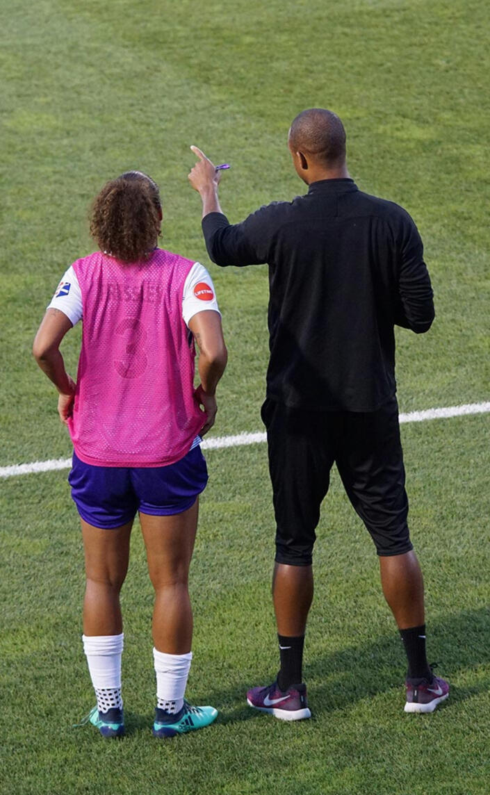 Entrenador de fútbol dando instrucciones finales a un suplente, enfatizando la preparación mental antes de entrar al partido.