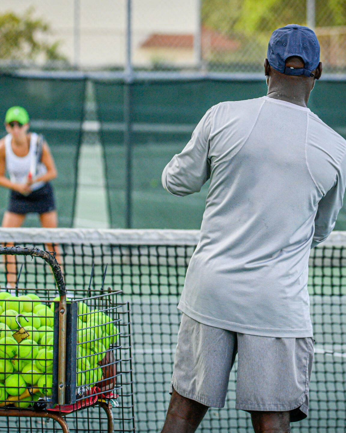 Entrenador de tenis preparando el saque para una jugadora, destacando refinamiento técnico y confianza entre atleta y entrenador.