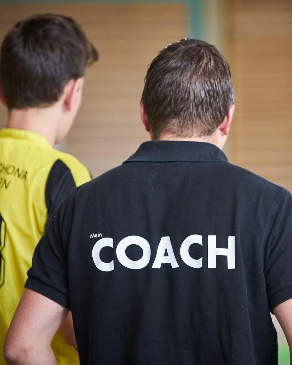 Entrenador guiando a un joven deportista en la pista, centrado en desarrollo temprano, orientación y construcción de una base mental sólida.