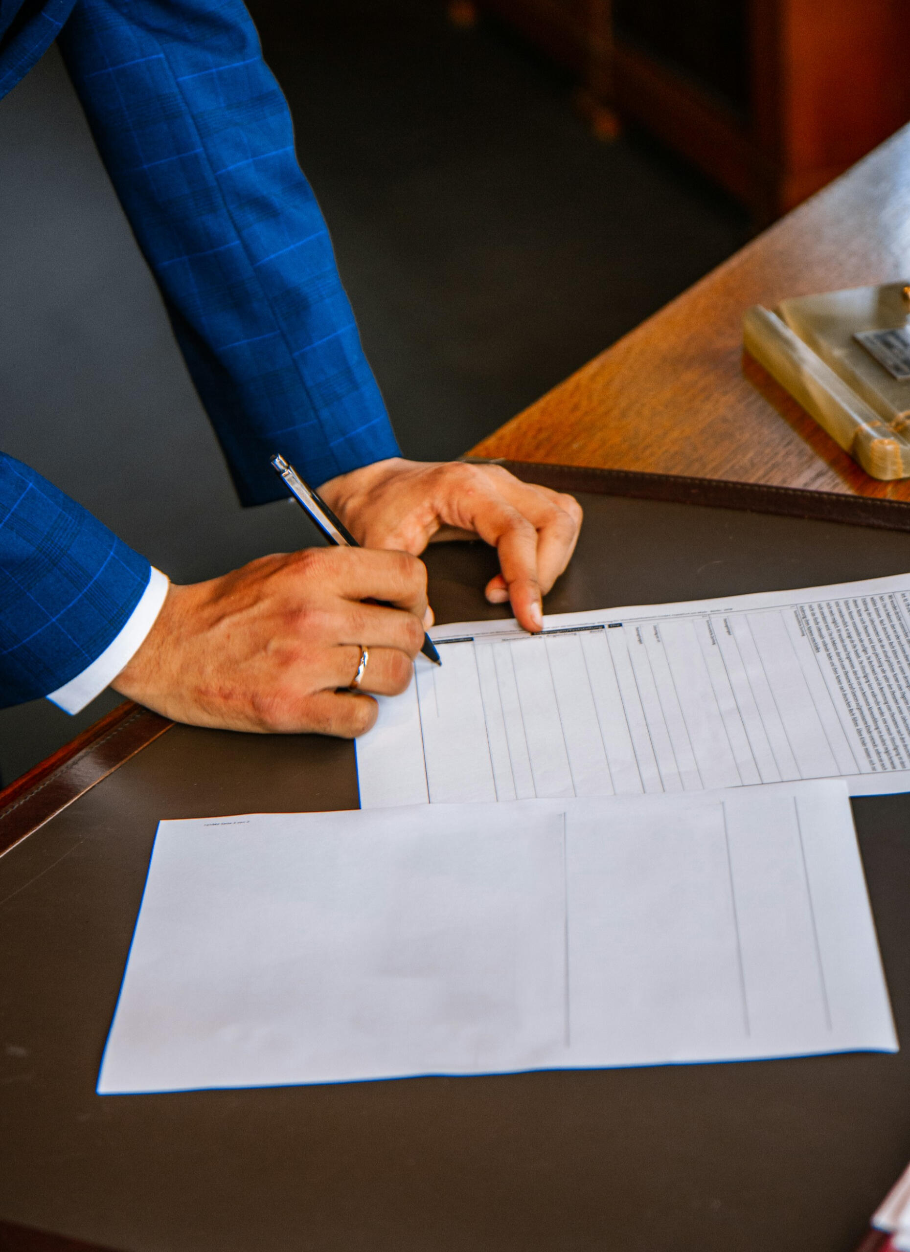 Primer plano de persona con traje firmando un contrato, representando acuerdos profesionales y sistemas de apoyo para jóvenes deportistas.